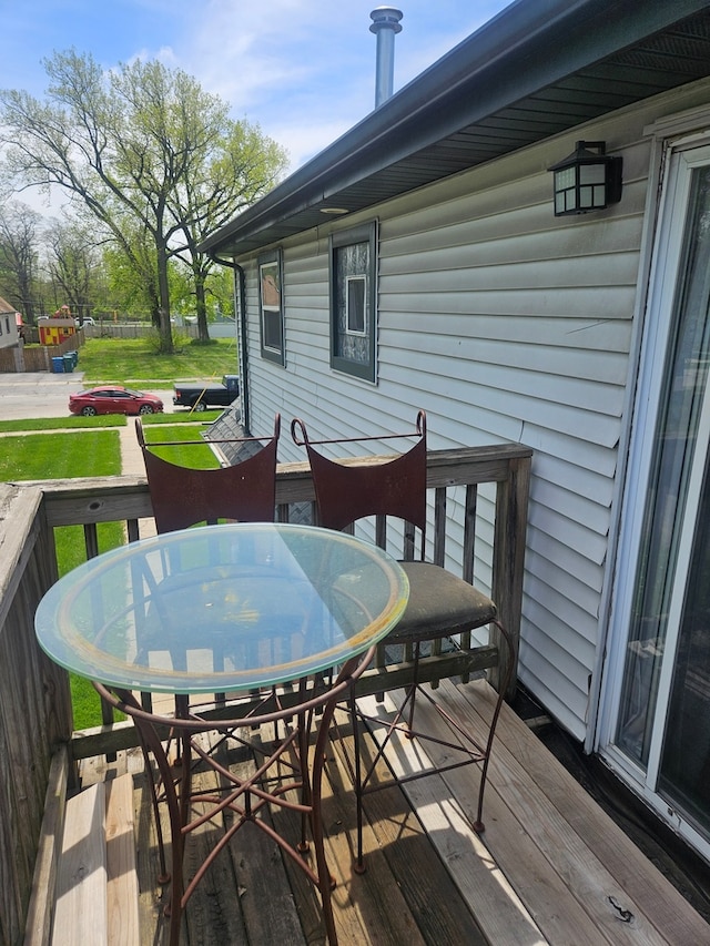 deck featuring outdoor dining space and a lawn