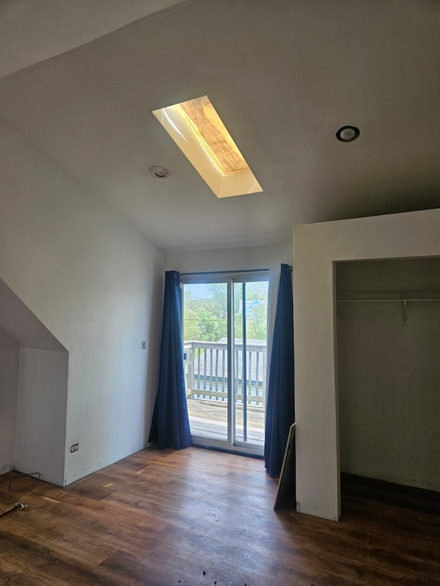 unfurnished bedroom featuring a skylight, access to exterior, wood finished floors, and a closet