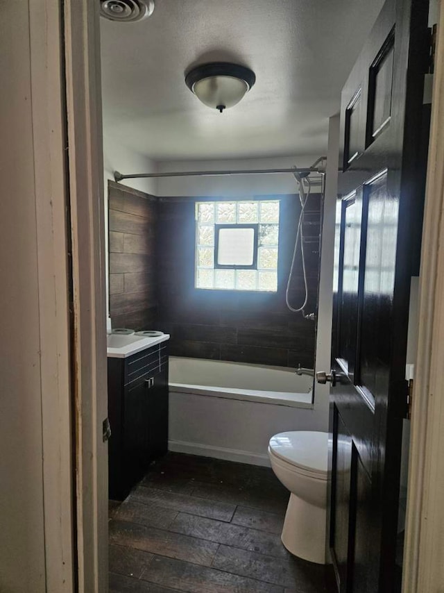 bathroom with hardwood / wood-style floors, toilet, vanity, and shower / bath combination