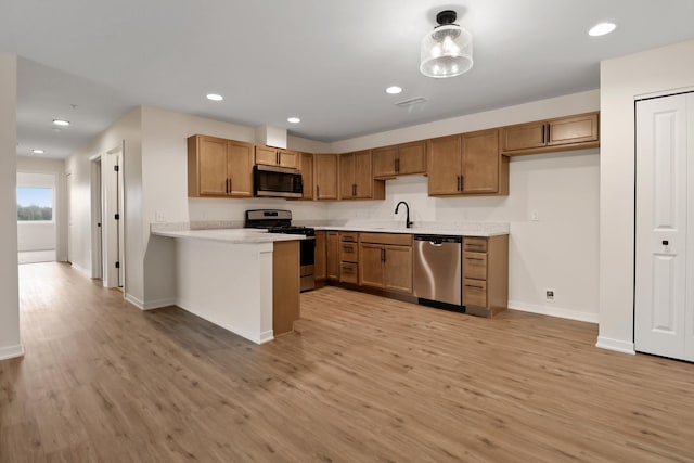 2034 W 75th Pl Unit 35, Merrillville, IN 46410 - kitchen with appliances with stainless steel finishes, a sink, light wood-style flooring, a peninsula, and brown cabinets