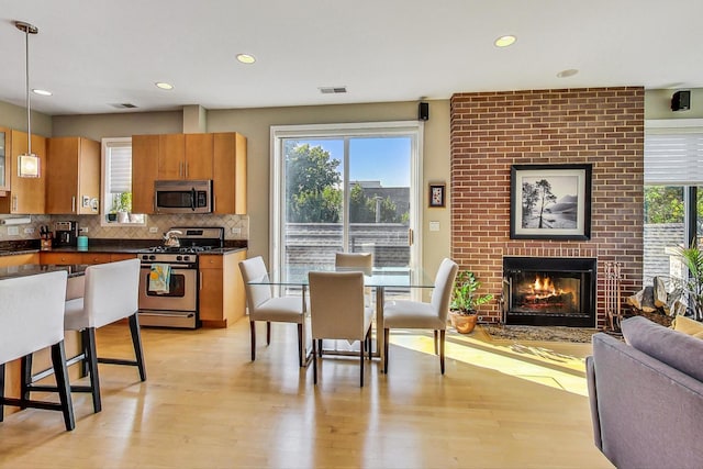 1133 N Wood St Unit 3S, Chicago, IL 60622 - kitchen with stainless steel appliances, dark countertops, light wood-type flooring, hanging light fixtures, and backsplash