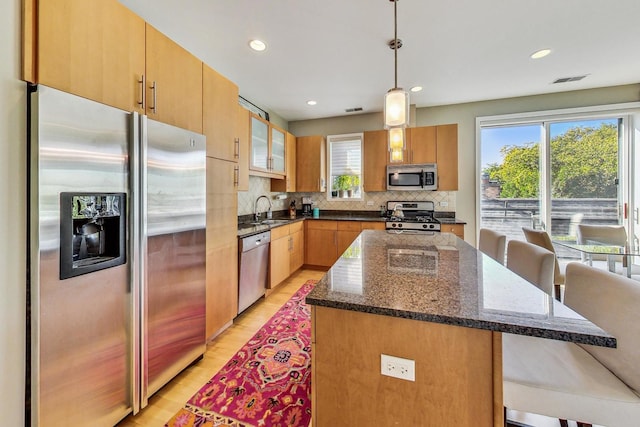 1133 N Wood St Unit 3S, Chicago, IL 60622 - kitchen with appliances with stainless steel finishes, dark stone counters, backsplash, light wood-style floors, and pendant lighting