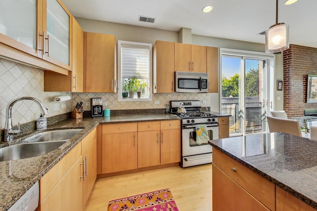 1133 N Wood St Unit 3S, Chicago, IL 60622 - kitchen featuring appliances with stainless steel finishes, a sink, light wood-style flooring, dark stone counters, and recessed lighting