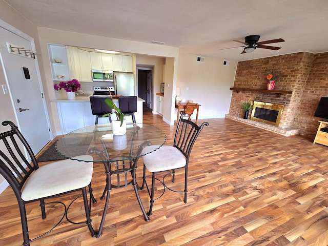5538 E Lake Dr Unit A, Lisle, IL 60532 - dining area with light wood-style flooring, a ceiling fan, a fireplace, and baseboards