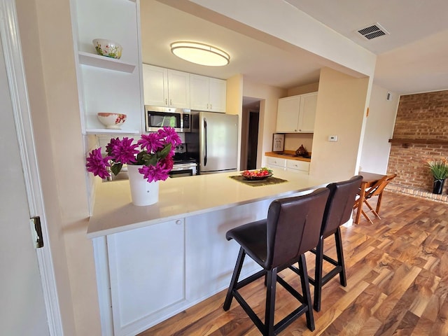 5538 E Lake Dr Unit A, Lisle, IL 60532 - kitchen featuring appliances with stainless steel finishes, a peninsula, white cabinets, open shelves, and a breakfast bar area