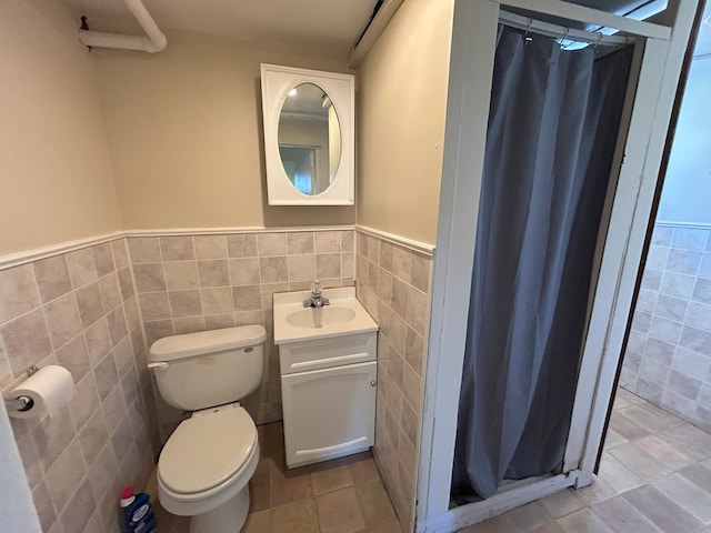 650 Enterprise St, Elgin, IL 60120 - bathroom featuring tile walls, a stall shower, toilet, vanity, and a wainscoted wall