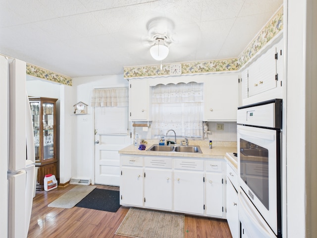 11314 S Green Bay Ave, Chicago, IL 60617 - kitchen featuring a sink, white oven, light countertops, light wood-style floors, and white cabinetry