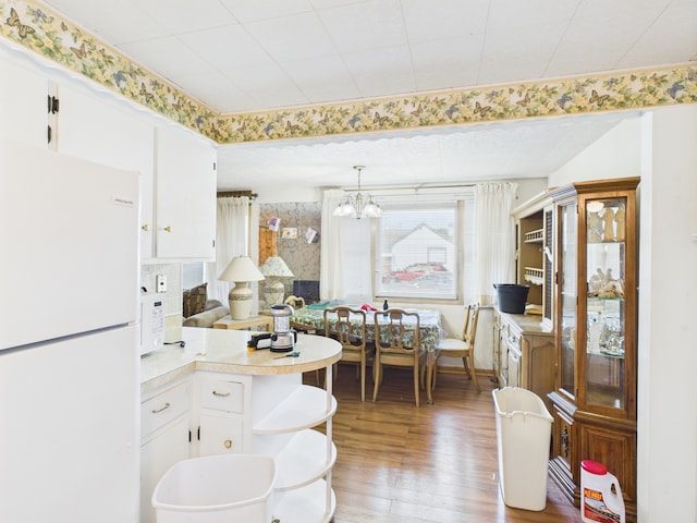 11314 S Green Bay Ave, Chicago, IL 60617 - kitchen with white appliances, wood finished floors, light countertops, white cabinets, and a chandelier