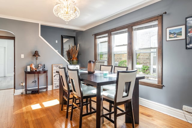5945 W Dakin St, Chicago, IL 60634 - dining space featuring arched walkways, light wood-style floors, baseboards, a chandelier, and crown molding