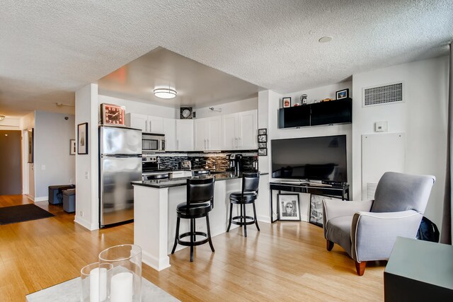 474 N Lake Shore Dr Unit 2012, Chicago, IL 60611 - kitchen with appliances with stainless steel finishes, a peninsula, dark countertops, light wood-type flooring, and a kitchen breakfast bar