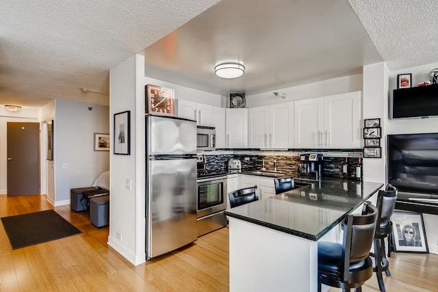 474 N Lake Shore Dr Unit 2012, Chicago, IL 60611 - kitchen with appliances with stainless steel finishes, a peninsula, decorative backsplash, light wood-type flooring, and a textured ceiling