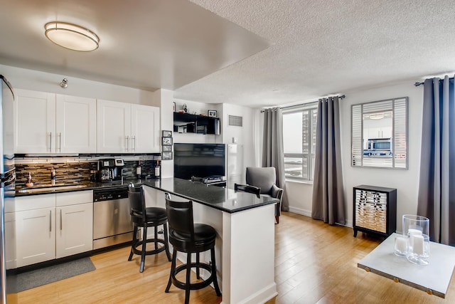 474 N Lake Shore Dr Unit 2012, Chicago, IL 60611 - kitchen featuring stainless steel appliances, a sink, dark countertops, a peninsula, and a textured ceiling
