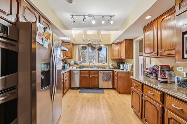 51 Oak Creek Dr, Burr Ridge, IL 60527 - kitchen featuring appliances with stainless steel finishes, brown cabinetry, light wood-style floors, a sink, and stone countertops