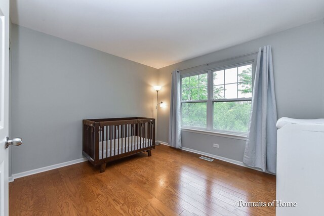 435 N Commerce St, Aurora, IL 60504 - bedroom with wood finished floors, baseboards, and a nursery area