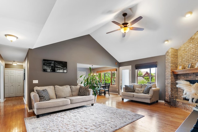 807 Meadow Ln, North Aurora, IL 60542 - living room featuring a ceiling fan, light wood finished floors, high vaulted ceiling, a brick fireplace, and baseboards