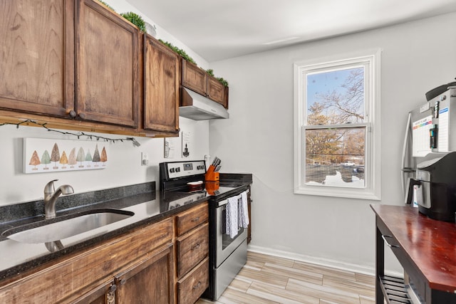 kitchen featuring stainless steel range with electric cooktop, under cabinet range hood, a sink, dark stone counters, and wood finish floors