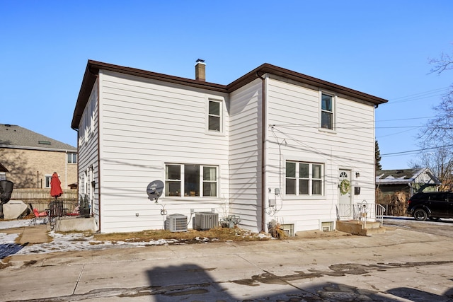 rear view of property featuring central AC and a chimney