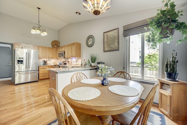 dining space featuring light wood-style floors, a chandelier, and high vaulted ceiling