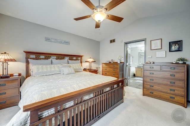bedroom with vaulted ceiling, light carpet, and ensuite bath