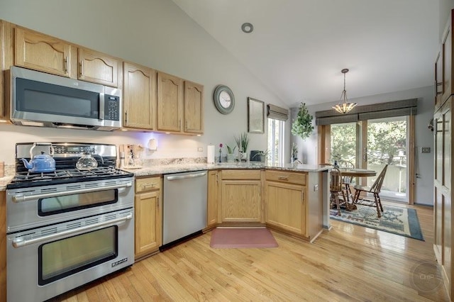 kitchen with stainless steel appliances, light brown cabinets, vaulted ceiling, a peninsula, and light wood-style floors