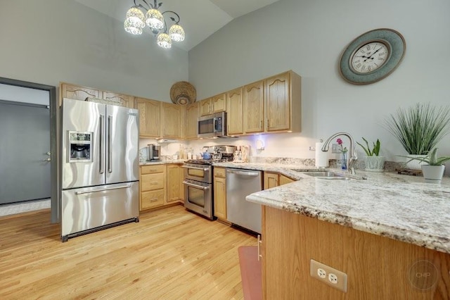 kitchen featuring stainless steel appliances, a sink, high vaulted ceiling, light stone counters, and light wood-style floors
