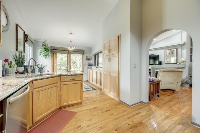 kitchen featuring a sink, dishwasher, light wood-style floors, light brown cabinets, and high vaulted ceiling