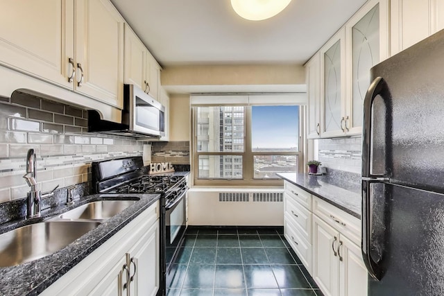 kitchen with black appliances, radiator, a sink, dark tile patterned floors, and white cabinets