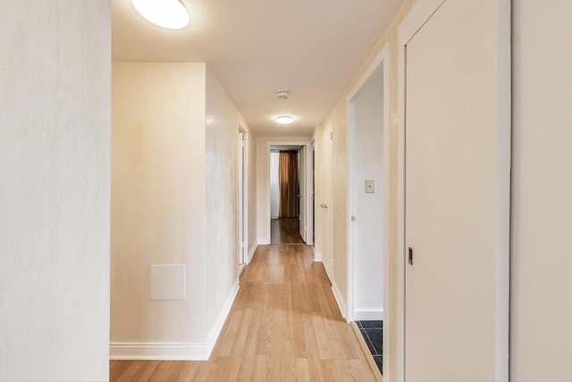 corridor with light wood-style floors and baseboards
