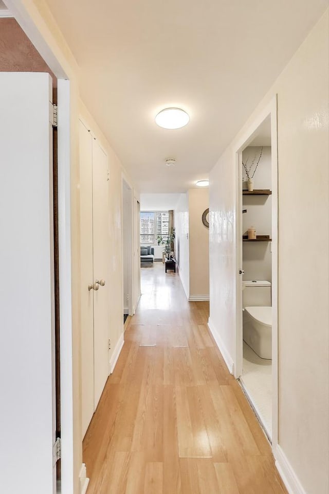corridor with light wood-style floors and baseboards