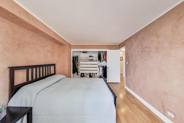 bedroom featuring wood finished floors, baseboards, and a closet