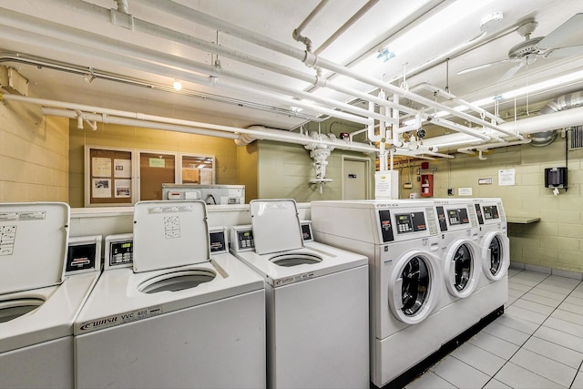 shared laundry room with independent washer and dryer, concrete block wall, and tile patterned floors