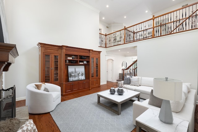 living area featuring a high ceiling, stairway, ornamental molding, baseboards, and wood finished floors