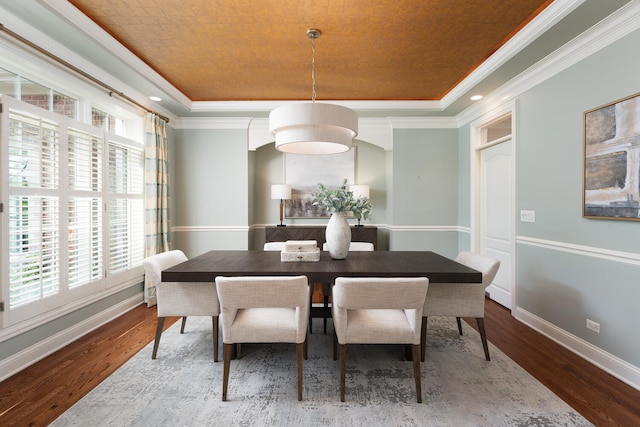 dining area featuring a tray ceiling, plenty of natural light, wood finished floors, and ornamental molding