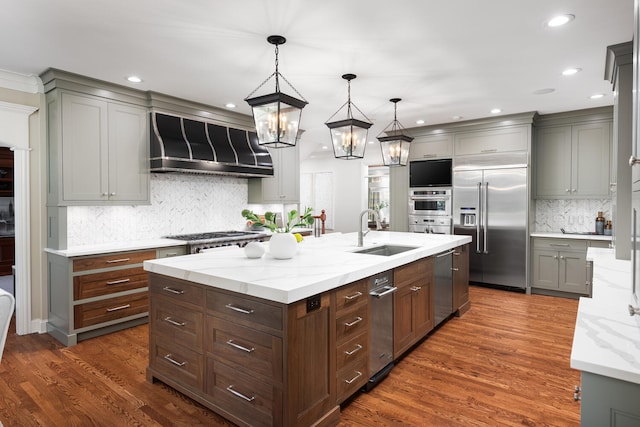 kitchen featuring a sink, stainless steel appliances, wall chimney exhaust hood, tasteful backsplash, and dark wood-style floors