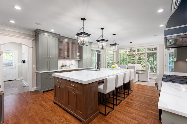 kitchen with a sink, gray cabinetry, a chandelier, crown molding, and light stone countertops