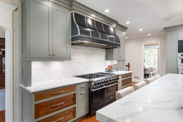 kitchen with range with two ovens, custom exhaust hood, oven, ornamental molding, and gray cabinetry
