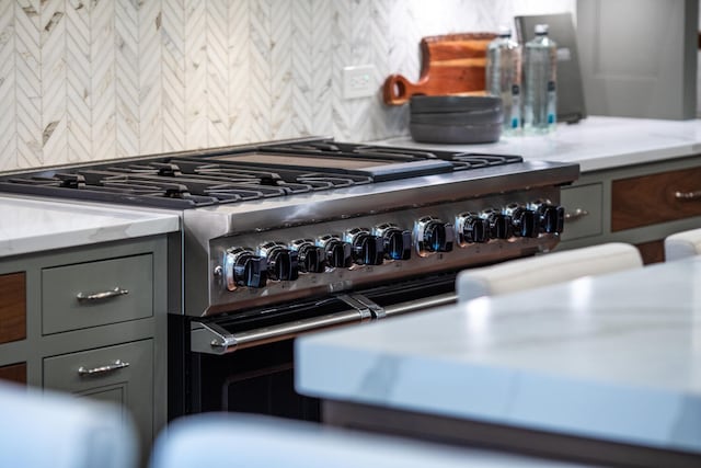 kitchen view of stainless steel stove, gray cabinets, and tasteful backsplash