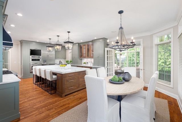 dining area featuring a chandelier, recessed lighting, wood finished floors, ornamental molding, and baseboards