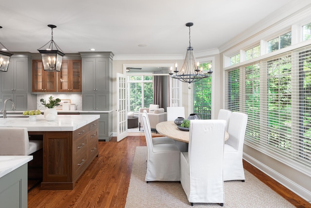dining area featuring a chandelier, wood finished floors, baseboards, and crown molding
