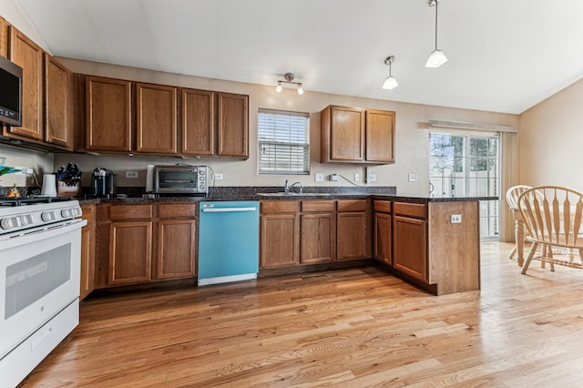 kitchen featuring dishwasher, white gas range, brown cabinets, and vaulted ceiling
