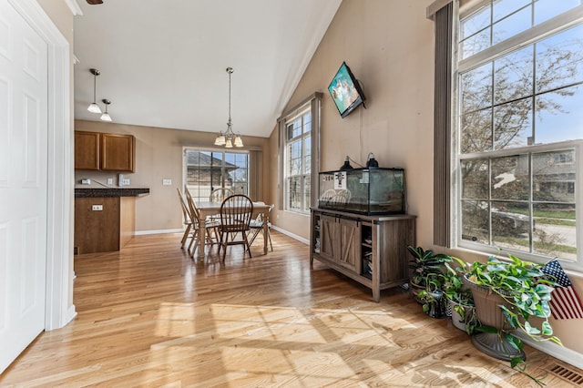 dining room with lofted ceiling, light wood-style floors, and baseboards