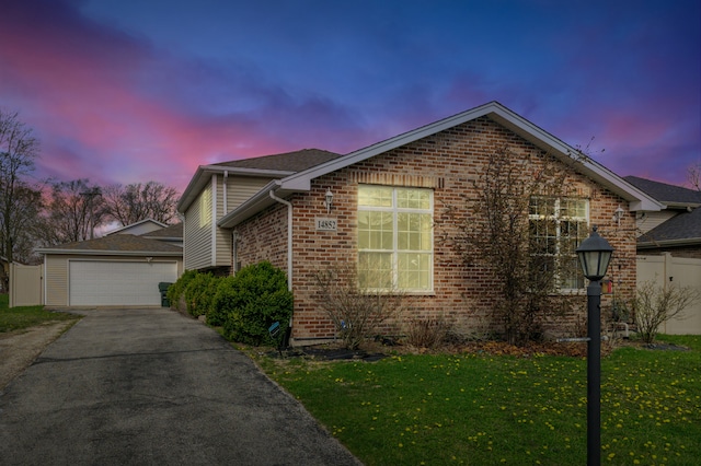 property exterior at dusk with brick siding, a yard, an outbuilding, and a garage
