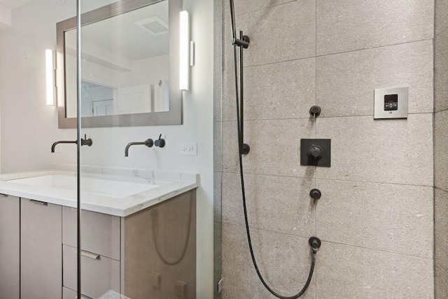 full bath featuring tiled shower and vanity