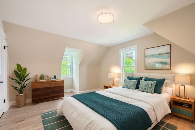 bedroom featuring multiple windows, light wood-style flooring, vaulted ceiling, and baseboards
