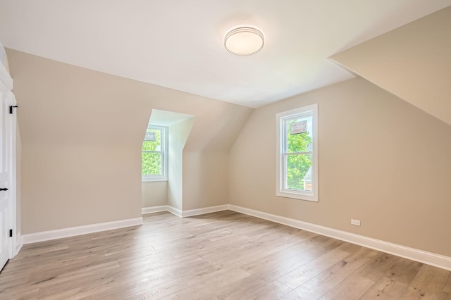 bonus room with lofted ceiling, healthy amount of natural light, light wood-type flooring, and baseboards