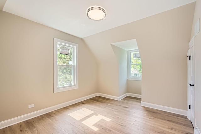 additional living space featuring healthy amount of natural light, light wood-type flooring, baseboards, and lofted ceiling