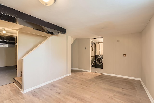 finished below grade area with washer / dryer, light wood-style flooring, and baseboards