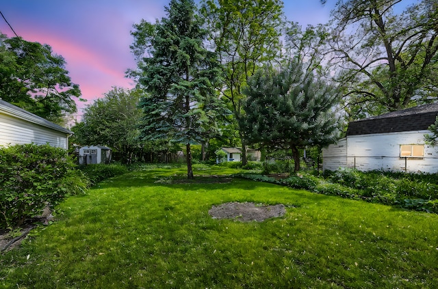 view of green lawn with a storage shed and an outbuilding