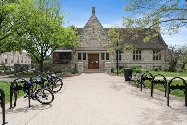 view of front facade with stone siding, french doors, fence, and a chimney