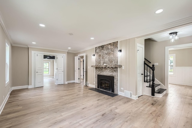 unfurnished living room featuring stairs, light wood-style floors, crown molding, a fireplace, and baseboards